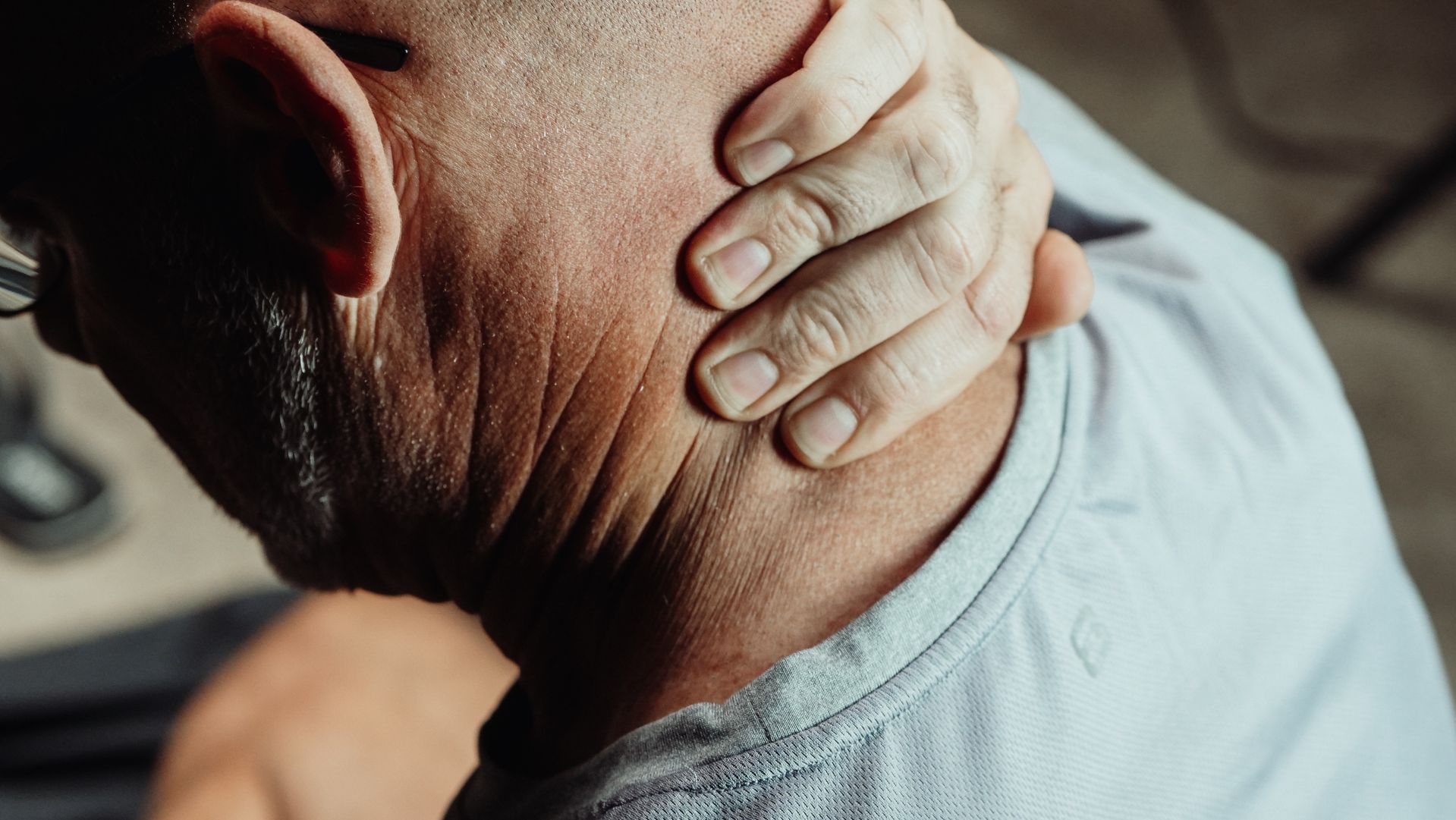 Person holding the back of the neck because of neck pain